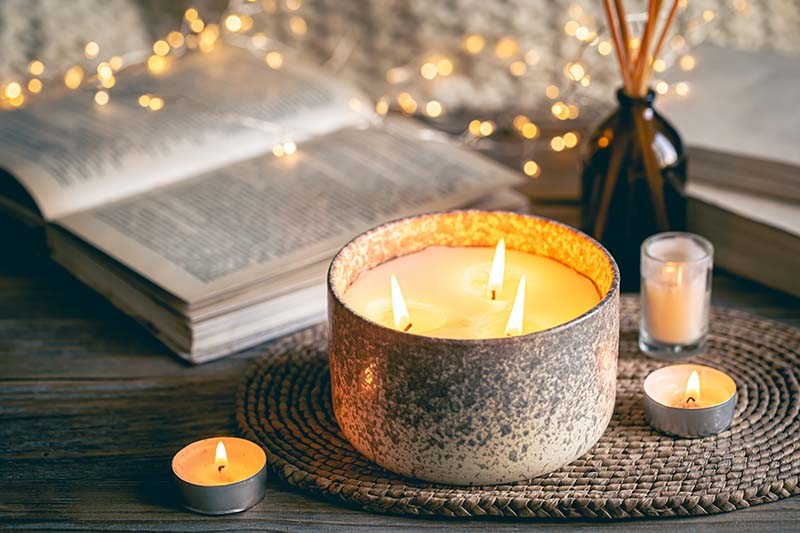 Cozy winter composition with candles on a blurred background with books. | freepik