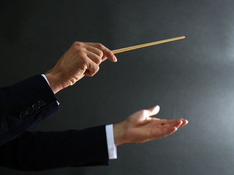 Music conductor hands with baton on black background | Adobe Stock